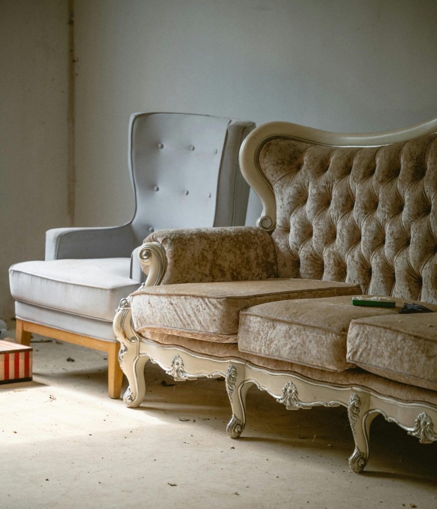 Ein Vintage-Sessel und ein Sofa in einem altmodischen Wohnzimmer, die Nostalgie und Eleganz ausstrahlen.